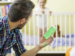 Father holding damaged smart phone and his little daughter in background