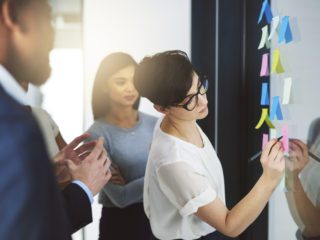 Coworkers with board full of post-its for planning
